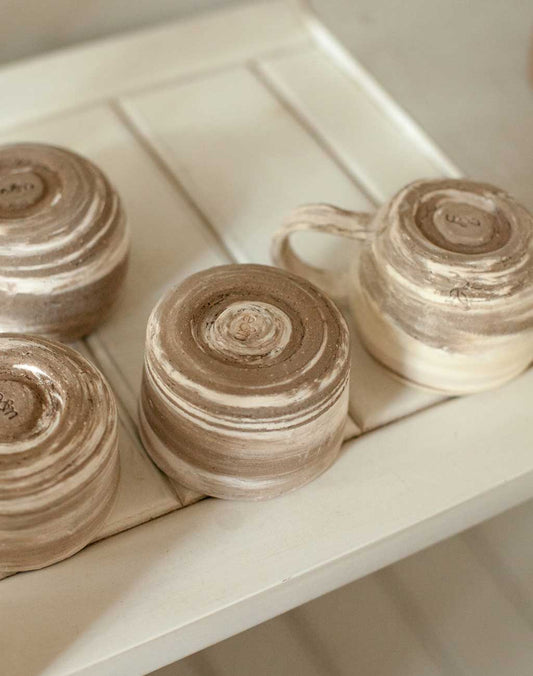 Earth and Nectar handmade pottery mugs drying on a shelf in the pottery studio before being fired in the kiln