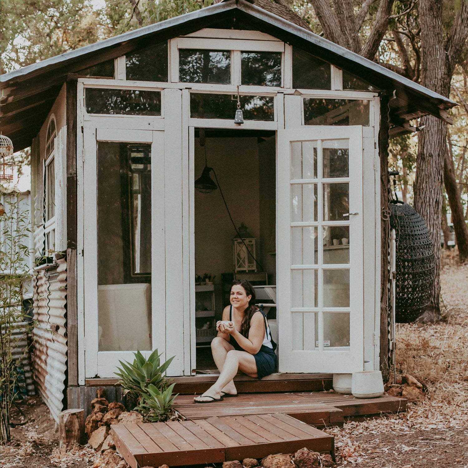 Hayley, Earth and Nectar owner and founder, sits in the doorway to her pottery studio in the Perth hills
