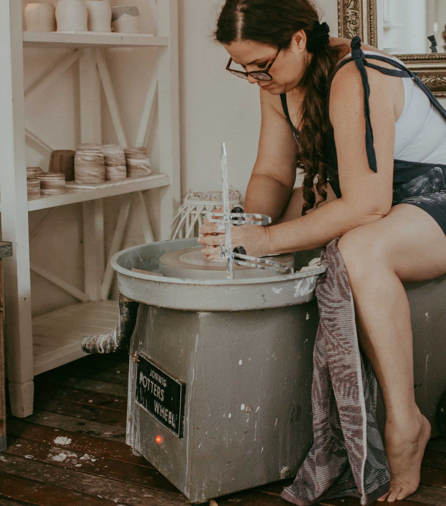 Hayley sitting at the pottery wheel hand throwing a clay mug in her Earth and Nectar studio on her farm in Roleystone in Perth